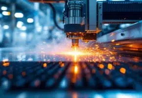 Lasersnijmachine snijdt plastic met oranje laserbundels, ventilatie zuigt dampen af in industriële werkplaats