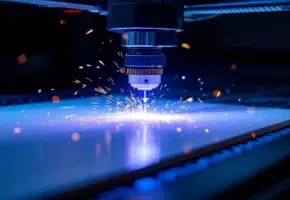Lasersnijmachine snijdt wit plastic met blauwe laserstraal, vonken verlichten precisieproces in industriële omgeving