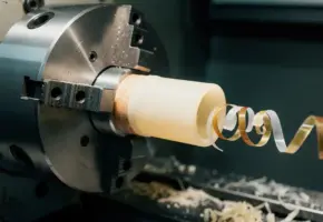Acrylcilinder in CNC-draaibank met spiraalvormige spaanders van transparant en amberkleurig plastic bij het snijgereedschap.