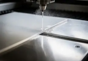Precisie waterstraalsnijding van doorschijnend plastic vel op industriële snijtafel, met fijne nevel in dramatisch bovenlicht.