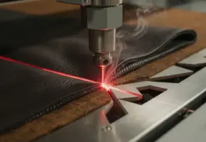 Lasersnijkop snijdt nauwkeurige geometrische vormen in donker leer en textiel, met dunne rookkringetjes langs de snijrand.