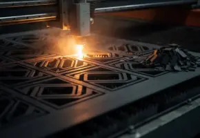 Lasersnijmachine snijdt nauwkeurig industrieel rubber met geneste geometrische vormen en minimale tussenruimte, oranje lasergloed op donkere fabrieksvloer.