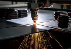 Laserkop snijdt door roestvrijstalen plaat met oranje vonkenregen, omgeven door precisie-gesneden rubber en plastic componenten.