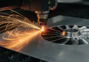 Lasersnijmachine snijdt aerospace-aluminium plaat met gouden vonkenregen, gedeeltelijk gesneden turbinecomponent zichtbaar op de snijmat.
